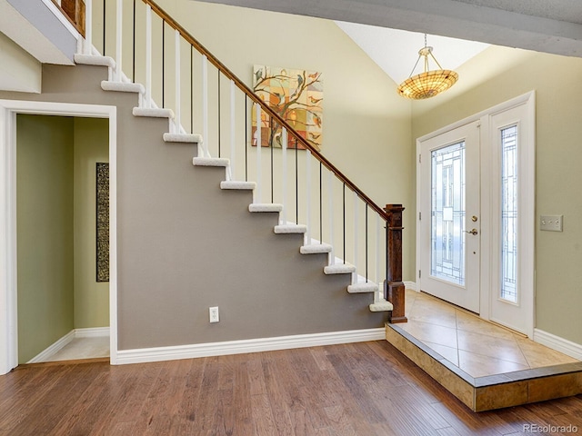 foyer with lofted ceiling, stairway, wood finished floors, and baseboards