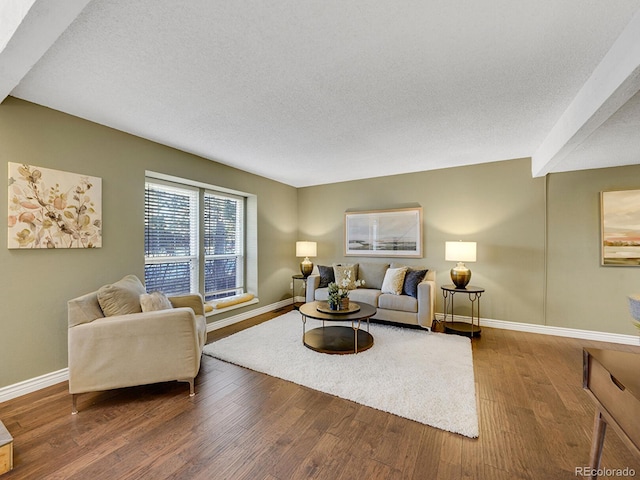 living room with a textured ceiling, baseboards, and wood finished floors