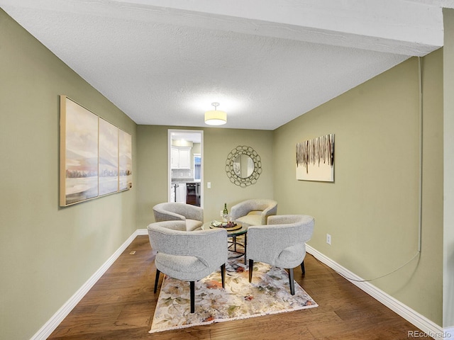 interior space with a textured ceiling, wood finished floors, and baseboards