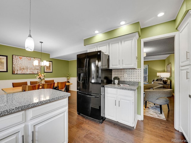 kitchen featuring white cabinets, dark wood finished floors, hanging light fixtures, and black fridge with ice dispenser