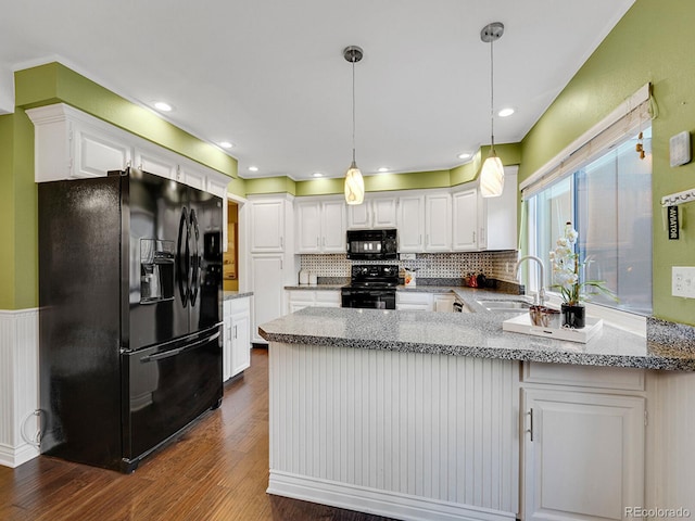 kitchen with a peninsula, dark wood-type flooring, a sink, white cabinetry, and black appliances