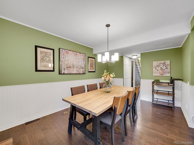 dining area with a wainscoted wall, visible vents, wood finished floors, and an inviting chandelier