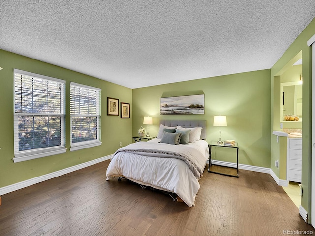 bedroom featuring a textured ceiling, wood finished floors, connected bathroom, and baseboards