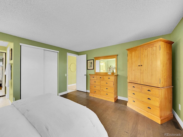 bedroom with baseboards, visible vents, dark wood-style flooring, a textured ceiling, and a closet