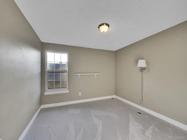 empty room with a textured ceiling, carpet, and baseboards