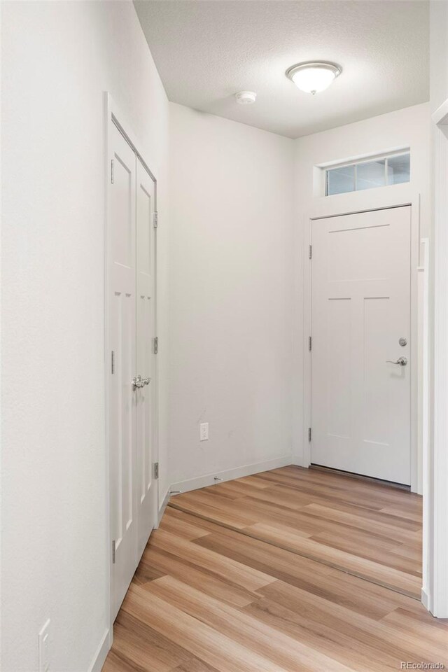 1849 S Helena St, Aurora, CO 80017 - doorway to outside with light wood finished floors, baseboards, and a textured ceiling