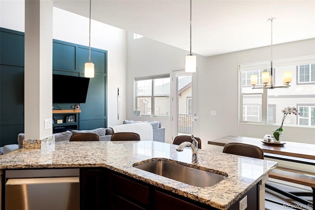 kitchen with a sink, open floor plan, a chandelier, and hanging light fixtures