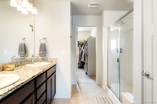 bathroom with a stall shower, tile patterned floors, double vanity, and a walk in closet