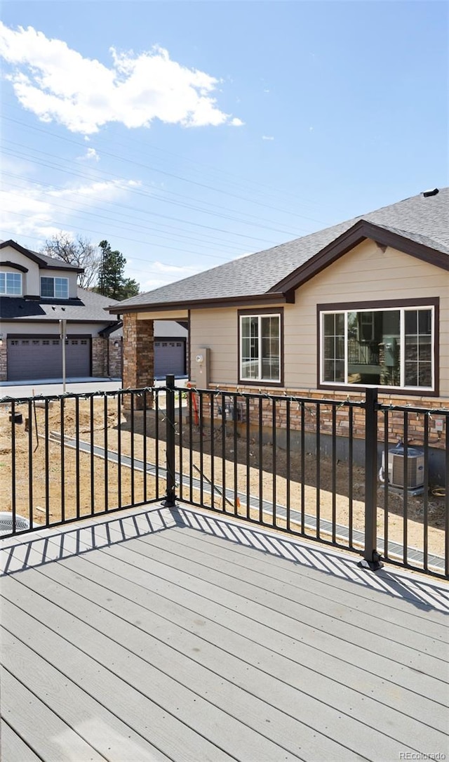 wooden deck featuring an attached garage and driveway