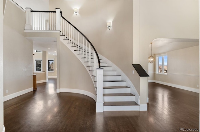 stairs with hardwood / wood-style flooring, a chandelier, and a towering ceiling