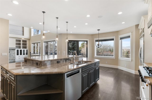 kitchen featuring sink, decorative light fixtures, stainless steel appliances, a large island, and light stone countertops