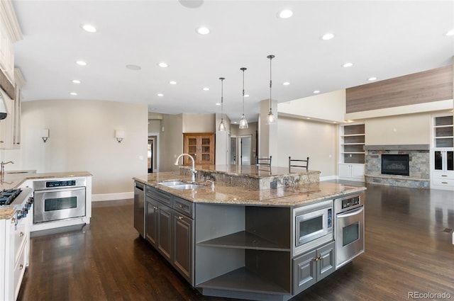 kitchen featuring sink, gray cabinetry, a large island with sink, stainless steel appliances, and white cabinets