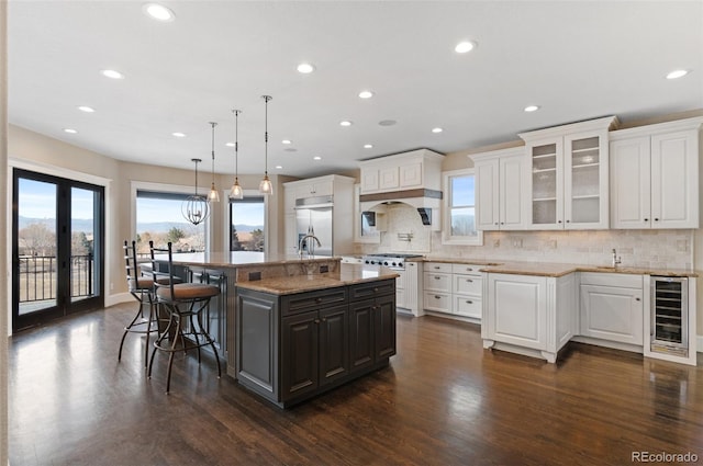 kitchen with wine cooler, a large island, hanging light fixtures, and white cabinets