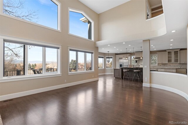 unfurnished living room featuring a towering ceiling, dark hardwood / wood-style floors, and a mountain view