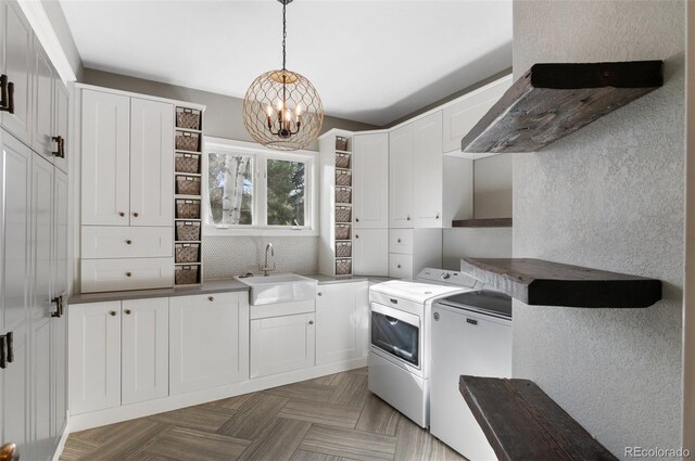 laundry area featuring sink, an inviting chandelier, cabinets, dark parquet floors, and washer and dryer