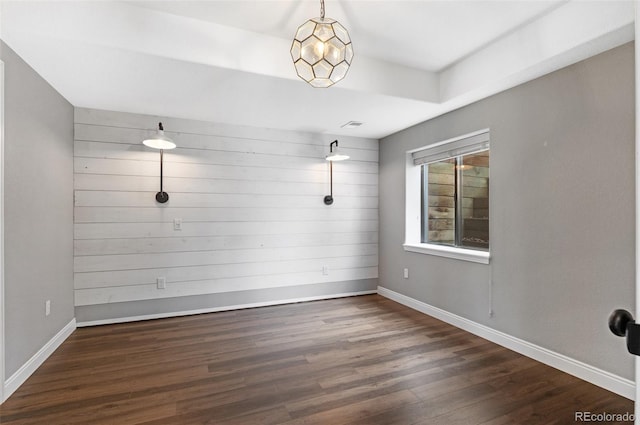 spare room featuring wooden walls and dark hardwood / wood-style flooring