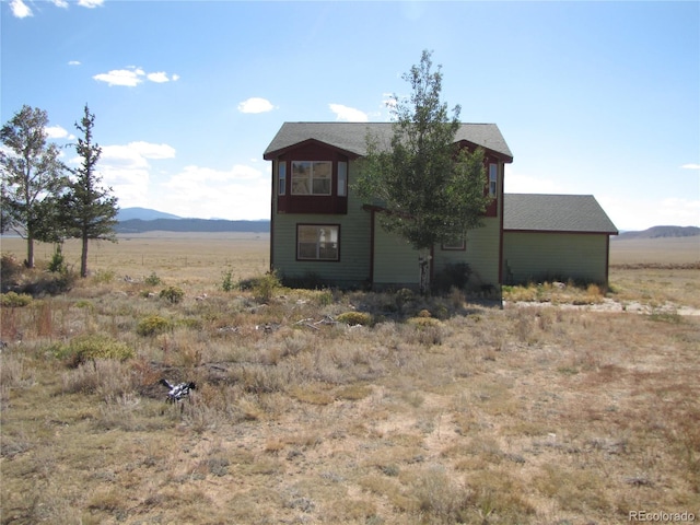 view of front of house with a mountain view and a rural view