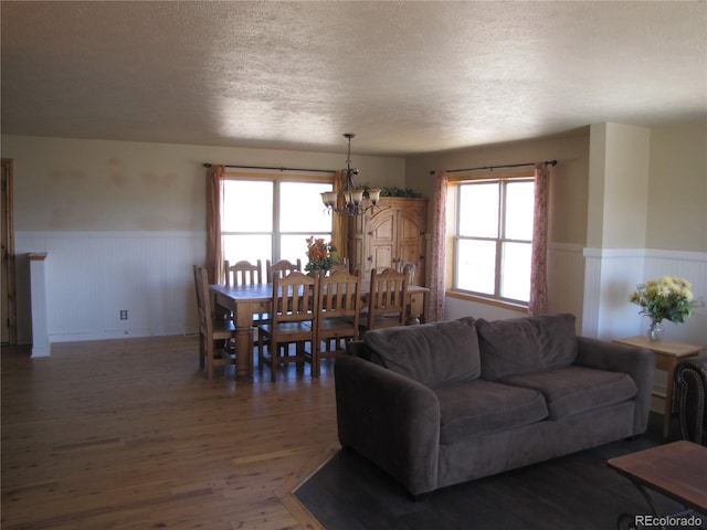 living room featuring a textured ceiling, a notable chandelier, and dark hardwood / wood-style flooring