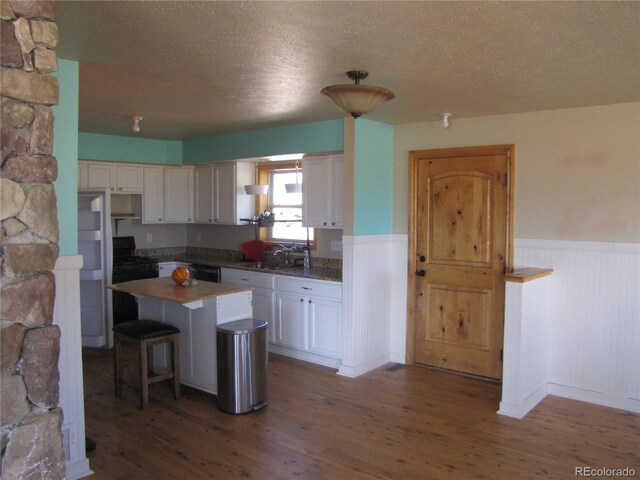 kitchen with a textured ceiling, a kitchen island, dark hardwood / wood-style floors, and white cabinetry