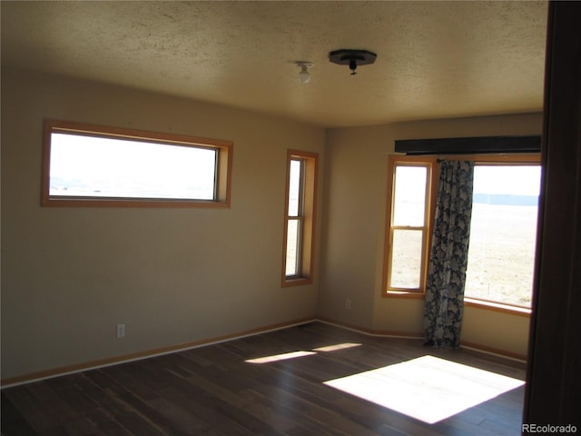 spare room with dark hardwood / wood-style flooring, a water view, and a textured ceiling