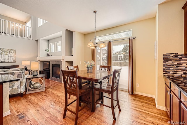 dining room featuring an inviting chandelier, a fireplace, and light hardwood / wood-style flooring