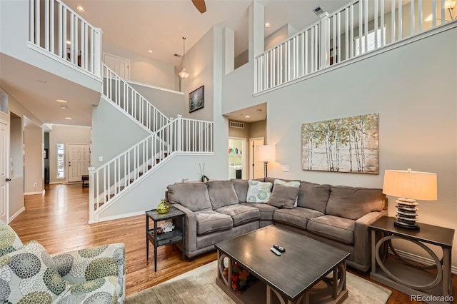 living area featuring stairway, visible vents, wood finished floors, and a towering ceiling