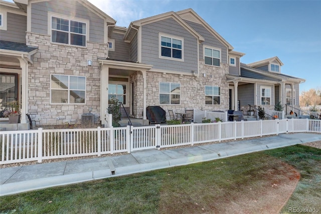 view of front of property featuring stone siding and a fenced front yard