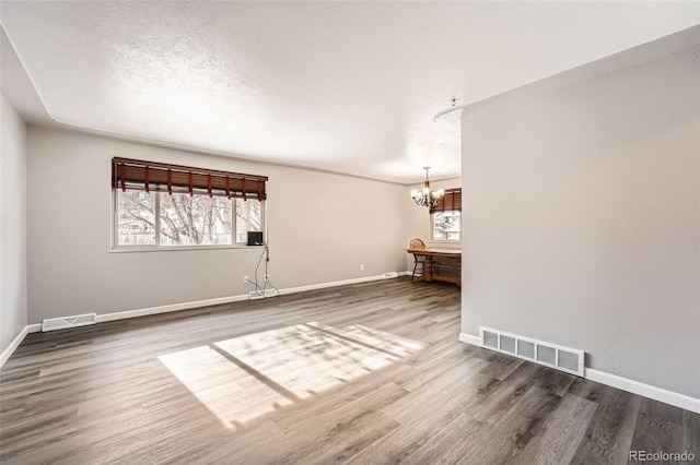 unfurnished living room with wood finished floors, visible vents, and baseboards