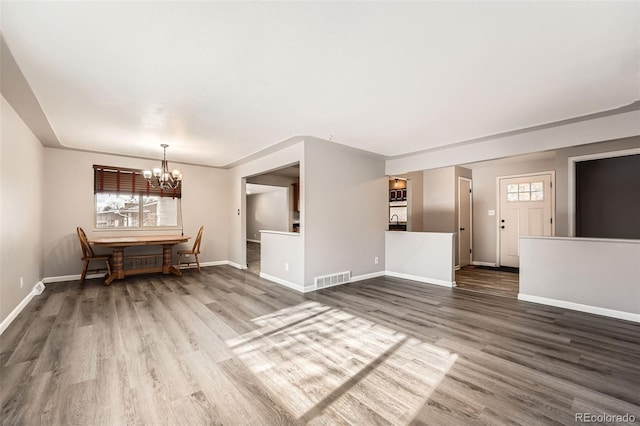 unfurnished dining area with visible vents, a notable chandelier, baseboards, and wood finished floors