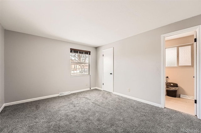 carpeted spare room with baseboards and visible vents