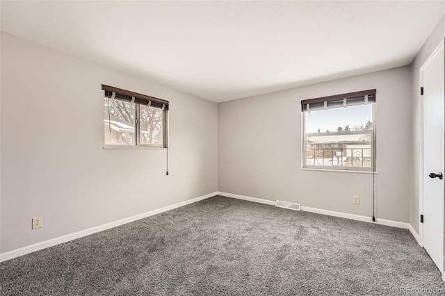 carpeted empty room featuring baseboards, visible vents, and a healthy amount of sunlight