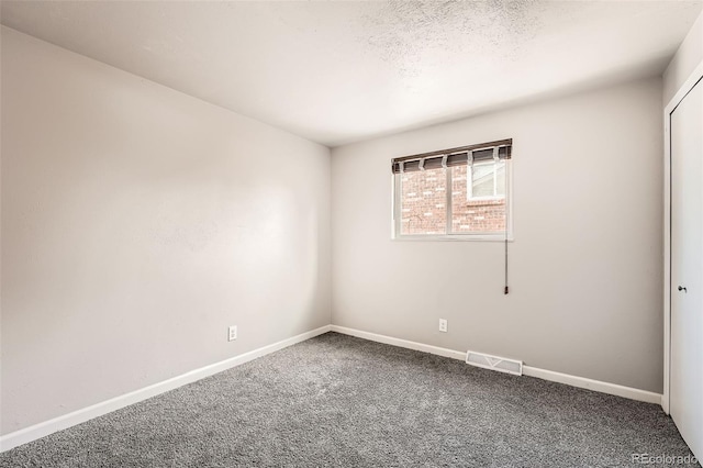 carpeted empty room with a textured ceiling, visible vents, and baseboards