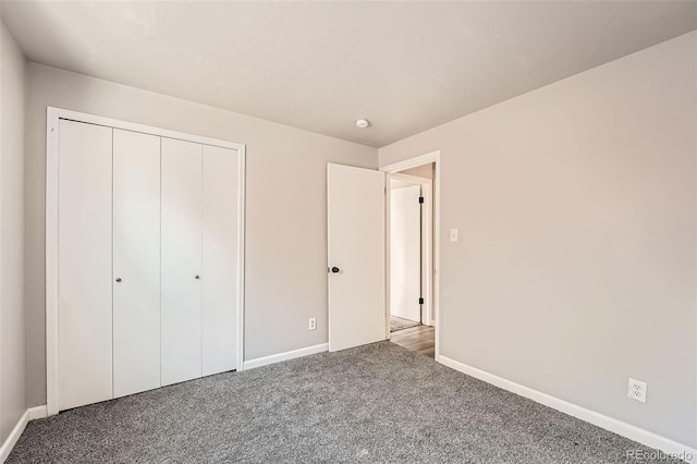 unfurnished bedroom with a closet, carpet flooring, and baseboards