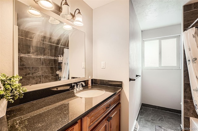 bathroom featuring curtained shower, vanity, baseboards, and a textured ceiling