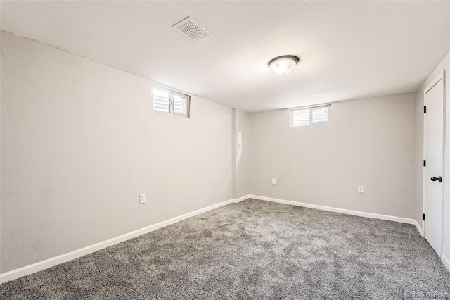 below grade area featuring a textured ceiling, carpet, visible vents, and baseboards