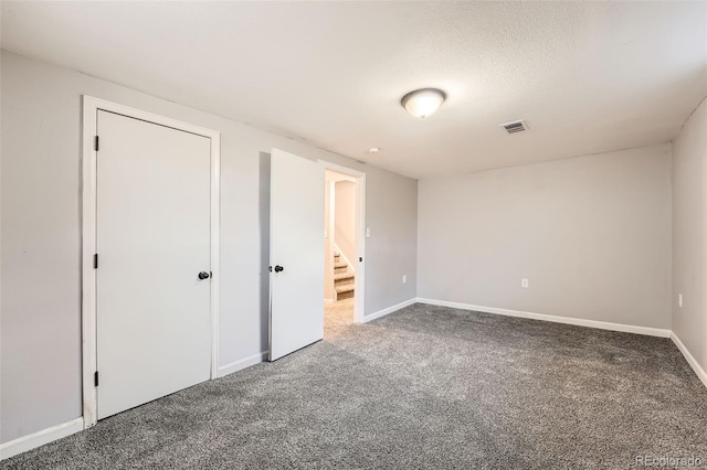 unfurnished bedroom featuring a textured ceiling, carpet floors, visible vents, and baseboards