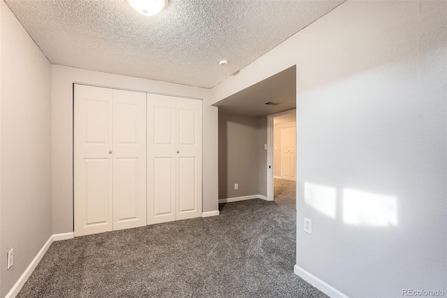 unfurnished bedroom with baseboards, dark carpet, and a closet