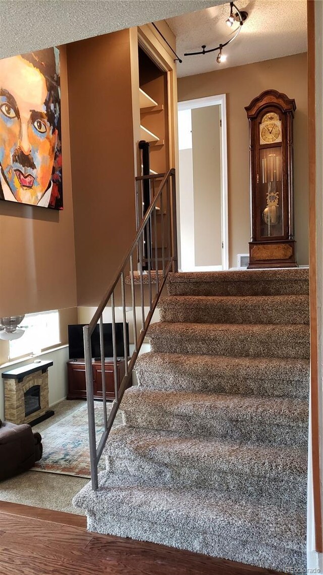 13661 W Tufts Ave, Morrison, CO 80465 - stairs with a fireplace, rail lighting, and a textured ceiling