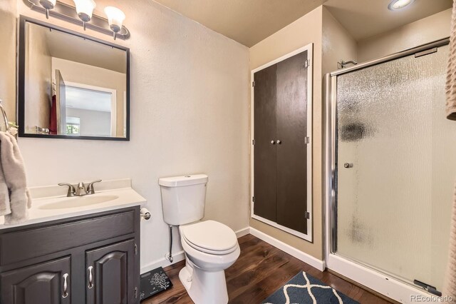 13661 W Tufts Ave, Morrison, CO 80465 - bathroom featuring vanity, wood finished floors, toilet, baseboards, and a shower stall