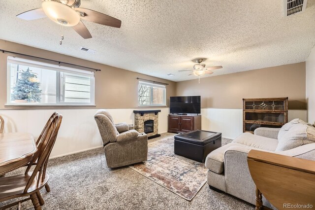 13661 W Tufts Ave, Morrison, CO 80465 - carpeted living area featuring a wainscoted wall, ceiling fan, a fireplace, and visible vents