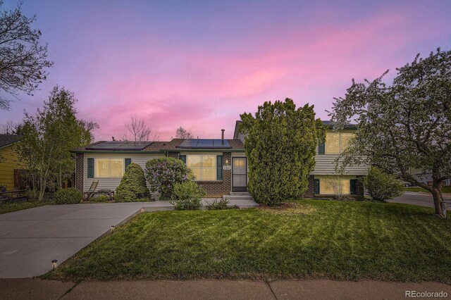 13661 W Tufts Ave, Morrison, CO 80465 - view of front facade with brick siding, a yard, and solar panels