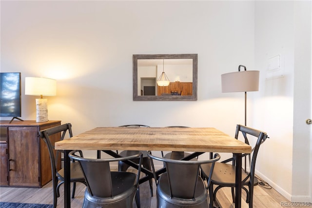 dining area featuring light wood-style flooring and baseboards