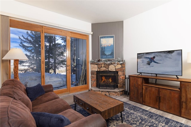 living room with a stone fireplace and wood finished floors