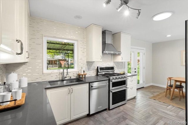6314 Brooks Dr, Arvada, CO 80004 - kitchen with wall chimney range hood, appliances with stainless steel finishes, a sink, and healthy amount of natural light