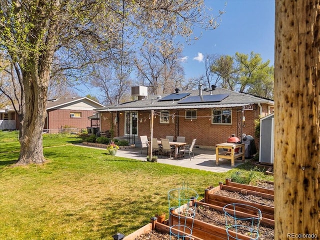 6314 Brooks Dr, Arvada, CO 80004 - back of property with a garden, a patio area, solar panels, and brick siding
