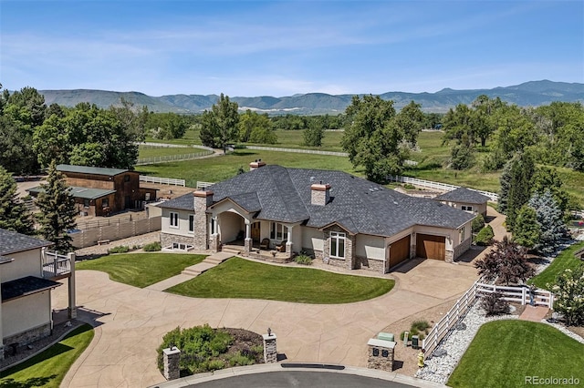 13962 W 76th Ln, Arvada, CO 80005 - view of front of home with stone siding, a chimney, an attached garage, curved driveway, and a mountain view