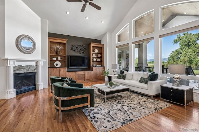 13962 W 76th Ln, Arvada, CO 80005 - living room with a ceiling fan, wood finished floors, a fireplace, recessed lighting, and built in shelves
