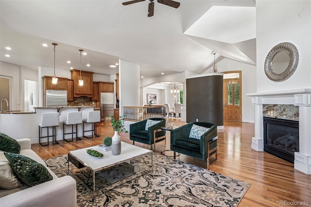 13962 W 76th Ln, Arvada, CO 80005 - living room featuring arched walkways, light wood-style floors, a ceiling fan, recessed lighting, and lofted ceiling