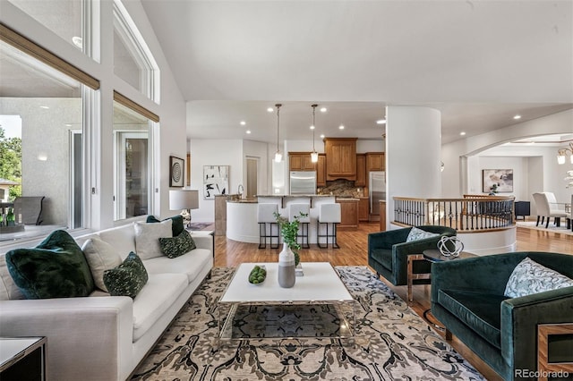 13962 W 76th Ln, Arvada, CO 80005 - living room featuring light wood-style flooring, arched walkways, recessed lighting, and lofted ceiling