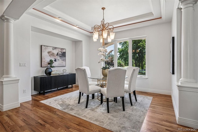 13962 W 76th Ln, Arvada, CO 80005 - dining room featuring decorative columns, a tray ceiling, wood finished floors, ornamental molding, and a chandelier